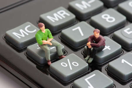 Two figurines sitting on calculator keys next to the percentage sign are talking about the concepts of interest rates, growth, recession, and inflation percentageの写真素材