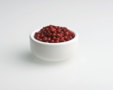 Pink Peppercorns In A White Dish Against A White backgroundの写真素材