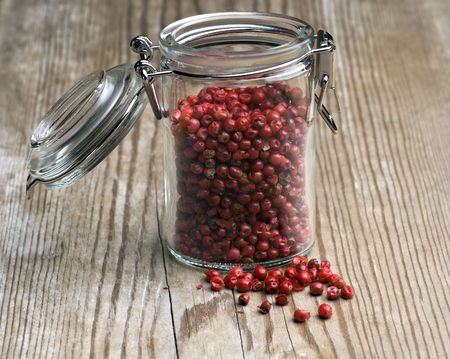Pink peppercorns In Spice Jar On Wooden Tableの写真素材