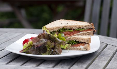 A Smoked Salmon Sandwich On A White Plate, On An Garden Tableの写真素材