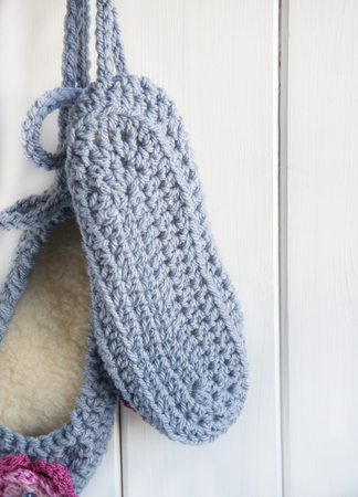 A Hand Crocheted Pair of Slippers Hanging Against A Wooden Door.の写真素材