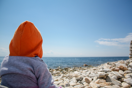 baby looks into the distance on the lakeの写真素材