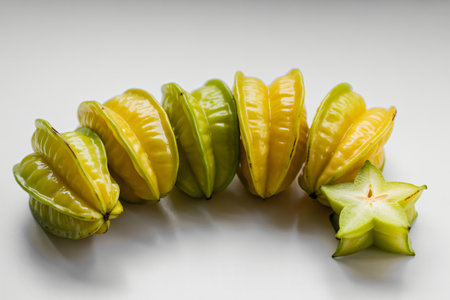 Star fruit carambola displays its unique star shape and vibrant yellow and green hues against a clean white background offering a fresh healthy and exotic food concept.の写真素材