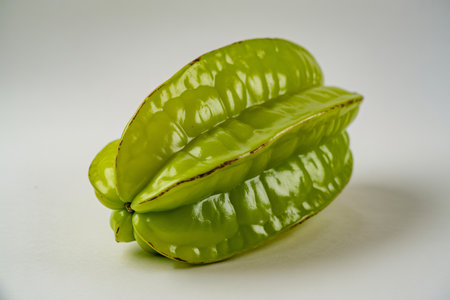 Starfruit displays its vibrant green color and distinctive star shape against a clean white background highlighting its unique texture and freshness making it ideal for healthy eating.の写真素材