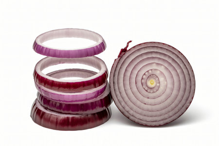 Red onion rings stacked next to a halved onion reveal concentric circles against a stark white backdrop showcasing fresh produce perfect for culinary creations and healthy eating.の写真素材