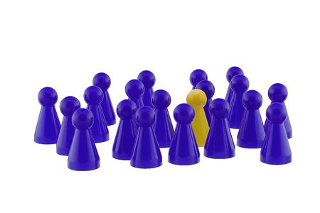 Single yellow playing figure standing out in a blue crowd.の写真素材