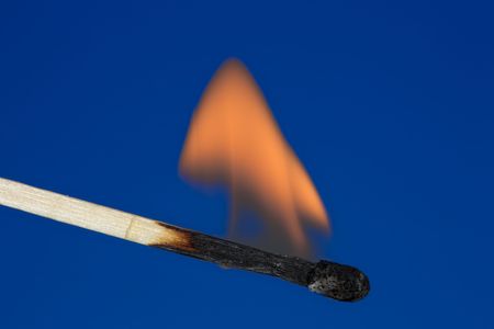 Photo of a single burning match against a uniform background.の写真素材