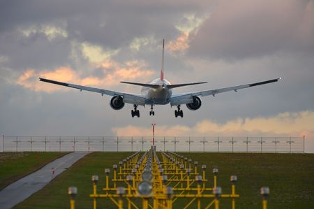 Photo of an airplane just before landing. Runway lights can be seen in the foreground.