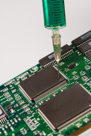Glass syringe filled with a colored liquid injecting into a circuit board.