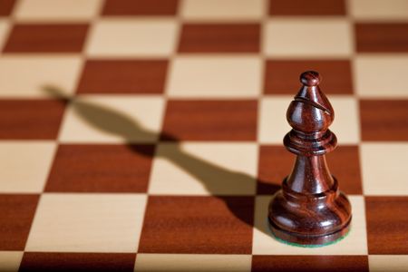Chess piece - a black bishop on a chessboard.の写真素材