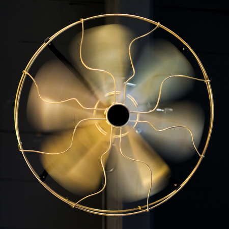 Close up brass ceiling fan on black wooden background.の写真素材