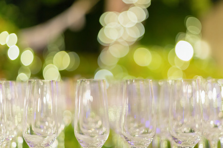Row of wine glasses in green background painted with beautiful bokeh.の写真素材
