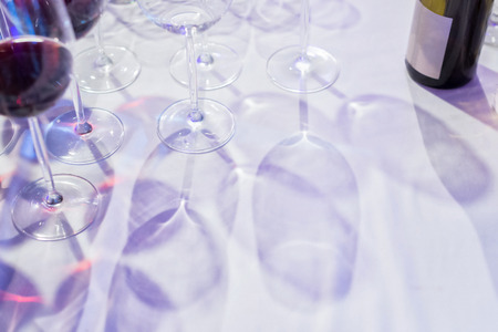 Glasses of wine shadowed on a white tablecloth. Useful to fill text in.の写真素材