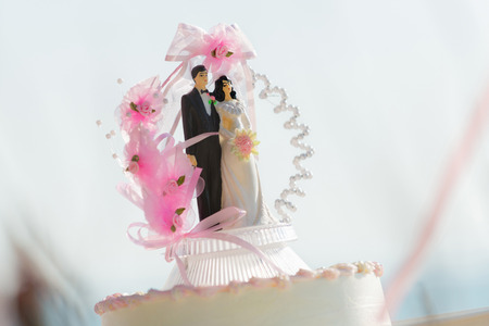 Doll weds of the bride and groom on a wedding cake that symbolizes the commitment to love one...