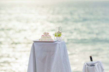 Table for the wedding ceremony, wedding cake, champagne, sunset, sea background.の写真素材
