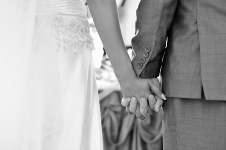 Groom holding bride's hand in outdoors wedding, holding hands newlyweds.の写真素材