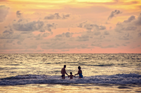 Seascape, beautiful sunset or sunrise with silhouette family holding hand and stand together.の写真素材