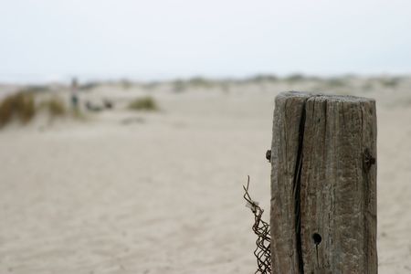 An old fence pole by the beach with a blurred backgroundの写真素材