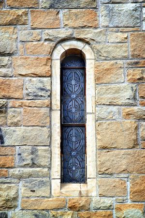 Narrow stained glass church window in a rock wallの写真素材