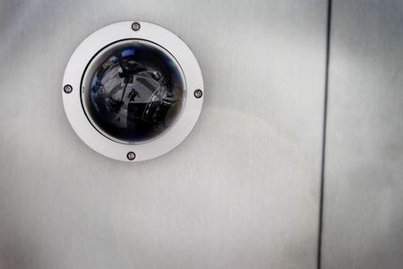 Round security camera in a silver metal ceiling.