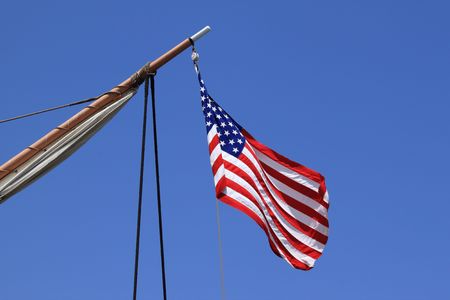 USA flag on an old sail ship with blue sky as backgroundの写真素材