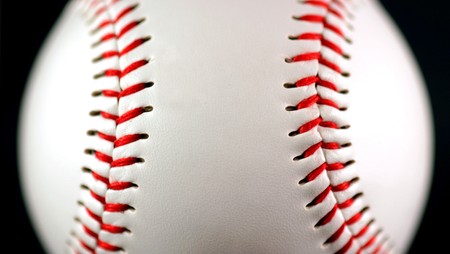 white leather baseball with red stitching on black backgroundの写真素材