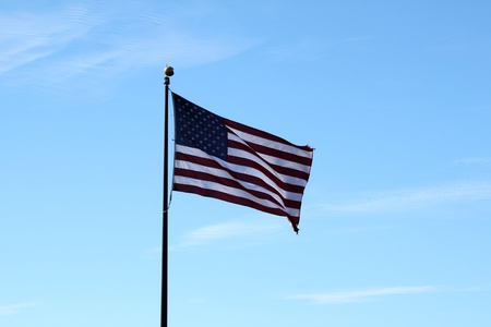 And old USA flag with a blue sky in the background.の写真素材