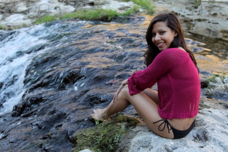 Hispanic woman sitting at water edge of a creek.の写真素材
