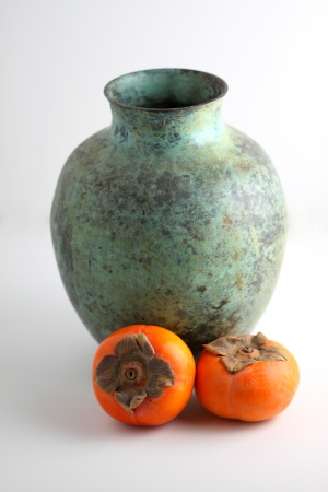 Persimmons with a green vase on white background の写真素材