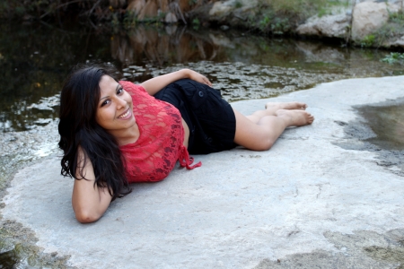 Hispanic woman lying at water edge of a creek の写真素材