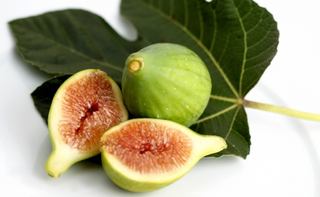 Close up of a green fig on white background with leave.の写真素材