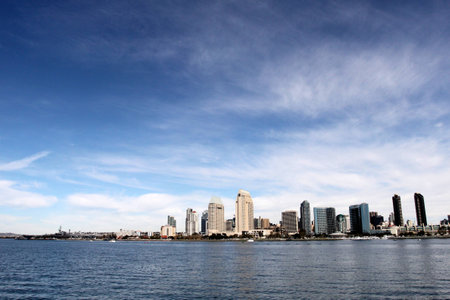 The skyline of San Diego with water in the front and cloudy blue sky in the background.の写真素材