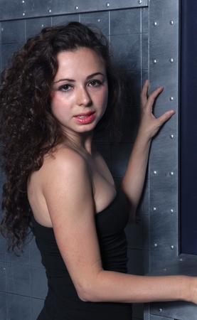 Woman with a black dress standing in front of a metal wall.の写真素材