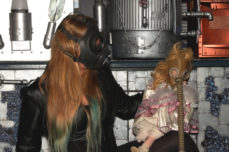 Woman with a gasmask and a puppet in front of a a wall.の写真素材