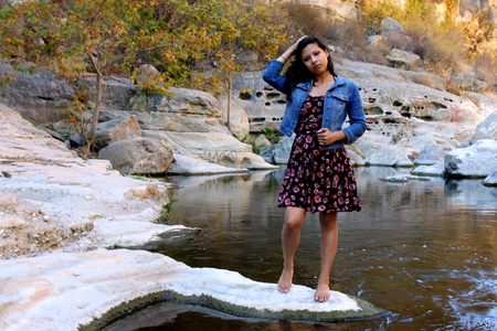 Young Hispanic woman near a creek with a dress and a blue jacket.の写真素材