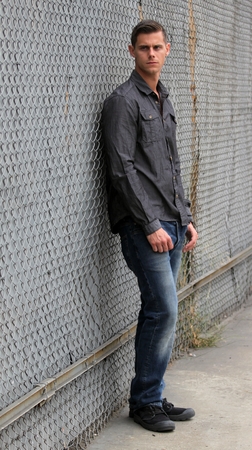 Portrait of a man standing in front of a chain link fence.の写真素材