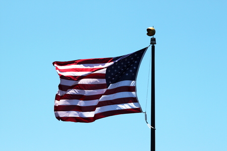 USA flag with a blue sky in the background.の写真素材