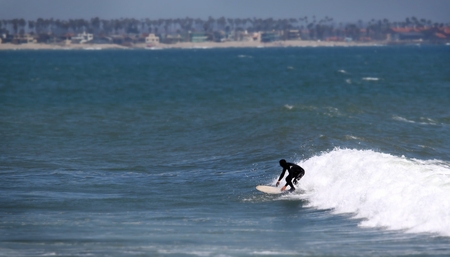 Surfer riding a white wave towards the shore.