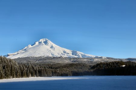Mount Hood, Oregon in winter with a frozen Trillium Lake in the foreground, the frozen lake partly shaded in the early morning.の写真素材