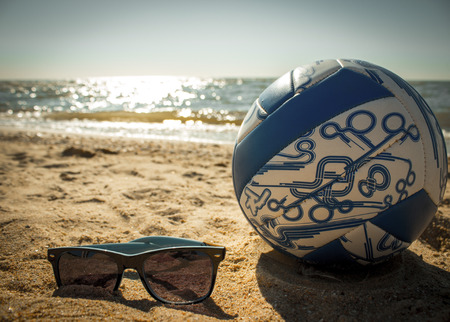 sunglasses, and volleyball on the sand near the seaの写真素材