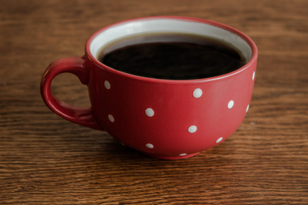 A red mug with coffee costs on a wooden tableの写真素材