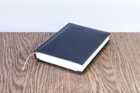 Simple blue leather note with yellow bookmark lies on a wooden table