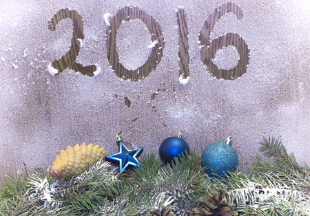 Christmas tree branches, Christmas toys and bumps on the background of the Frozen wall with the inscription pattern sixteen and twenty. Happy New Year and Merry Christmas holidaysの写真素材