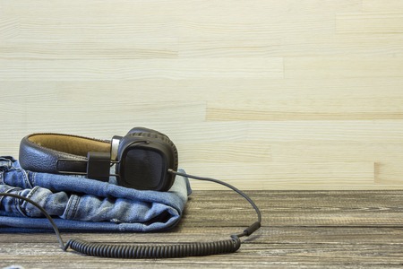 The old faded jeans and headphones are in the wooden background.の写真素材