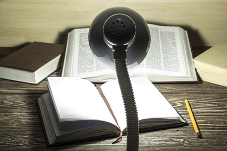 The book is illuminated by light from a lamp on a table in a dark room. Focus on lamp. Back viewの写真素材