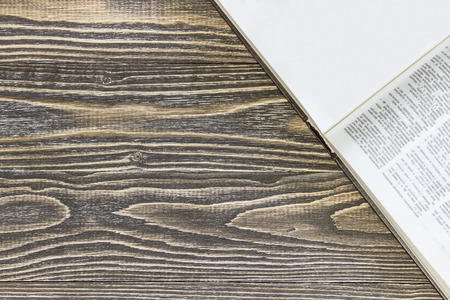 An open empty book is on a wooden background. Top view