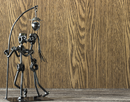 Statuette of a loving couple kissing under a lamp made of metal screws and rods on a wooden backgroundの写真素材