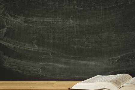 old covered text book, lying opened on a blank school or college classroom desk. Blackboard background. Mockupの写真素材