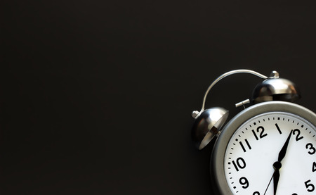Classic alarm clock with bells and arrows on background from black chalkboard. Top view. Close up....