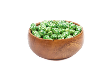 Green dragee in a wooden bowl isolated on white background. close-up.の写真素材